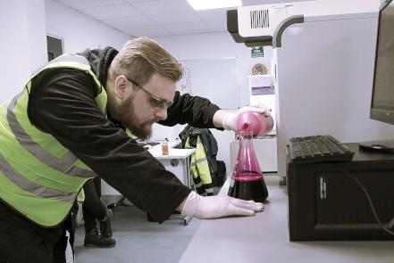 lab worker pours chemicals into a container during the creation of a new product